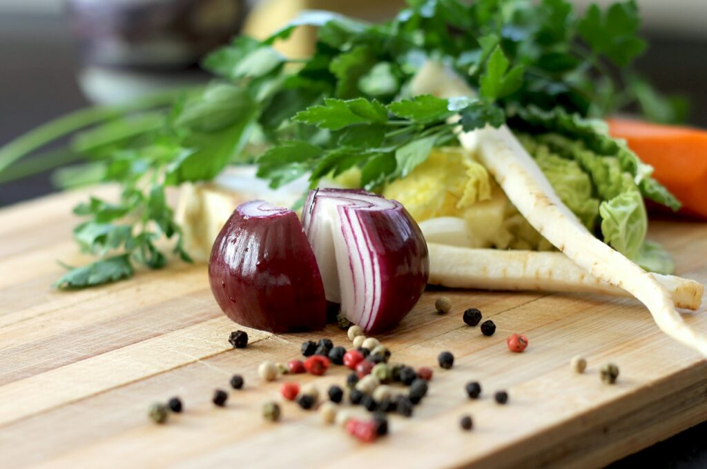 Cebolla roja sobre una tabla de cortar de madera, lista para ser utilizada en una receta que promueve la salud intestinal y bienestar mental.