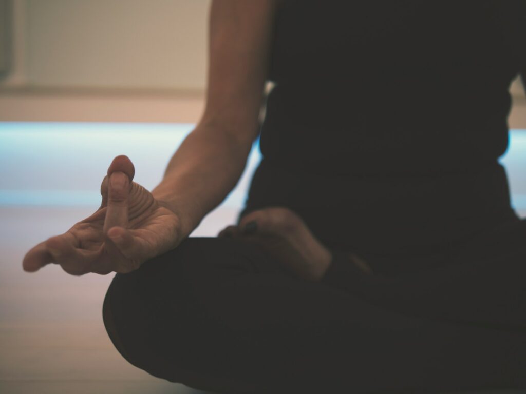 Persona practicando yoga en el suelo, conectando el cuerpo y la mente a través del ejercicio para la salud mental.