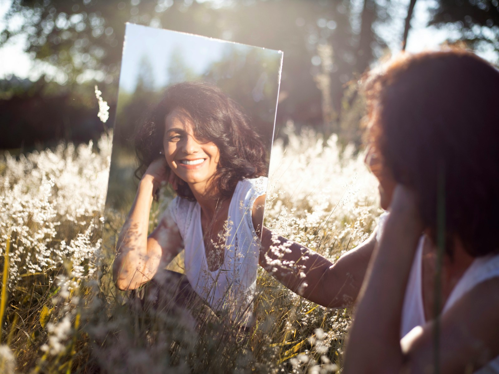 Mujer en camisa floral azul y blanca tocándose el rostro, reflejando tranquilidad y autocuidado, promoviendo hábitos saludables