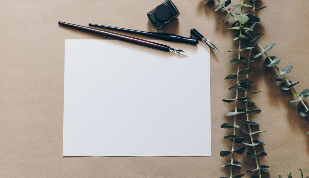 Papel en blanco junto a bolígrafos, simbolizando la reflexión sobre la salud mental en la era digital.