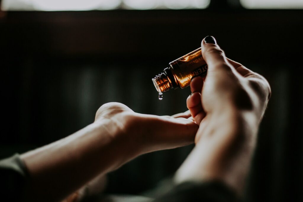 Manos aplicando gotas de aceite esencial, destacando el cuidado y la salud de la piel.